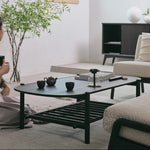 Modern living room with a black coffee table, white sofa, and decorative elements.