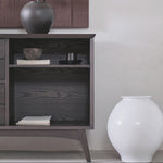 Dark wooden side table with a lamp and decorative items against a white wall.