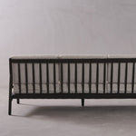 Sofa with black frame and gray cushion against a plain background