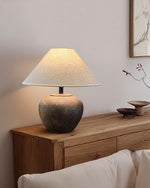 Table lamp with a textured base on a wooden side table against a neutral wall.