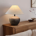 Table lamp with a textured base on a wooden side table against a neutral wall.