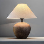 Table lamp with a textured base and beige shade on a gray background