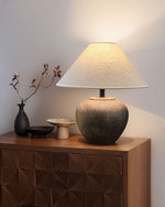 Table lamp on a wooden cabinet with decorative items against a white wall