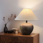 Table lamp on a wooden cabinet with decorative items against a white wall