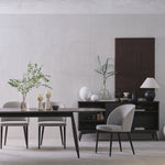 Modern dining room with a table, chairs, and decorative items against a plain wall.