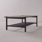 Black metal coffee table with glass top on a plain background