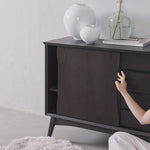 Dark wooden sideboard with decorative vases and a plant against a light gray wall.