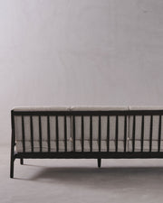 Sofa with black frame and gray cushion against a plain background