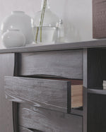 Wooden cabinet with drawers and decorative items on a light gray background