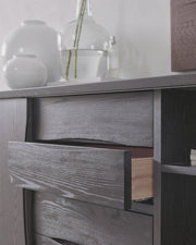 Wooden cabinet with drawers and decorative items on a light gray background