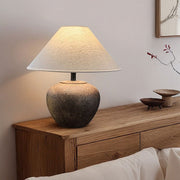 Table lamp with a textured base on a wooden side table against a neutral wall.