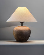 Table lamp with a textured base and beige shade on a gray background
