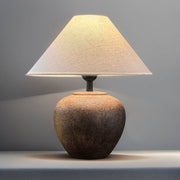 Table lamp with a textured base and beige shade on a gray background