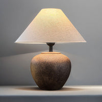 Table lamp with a textured base and beige shade on a gray background