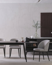 Modern dining room with a black table and gray chairs against a white wall.