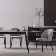 Modern dining room with a black table and gray chairs against a white wall.