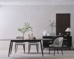 Modern dining room with a table, chairs, and decorative items against a plain wall.