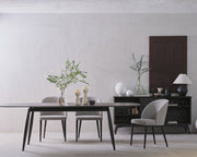 Modern dining room with a table, chairs, and decorative items against a plain wall.