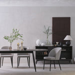 Modern dining room with a table, chairs, and decorative items against a plain wall.