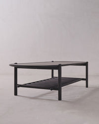 Black metal coffee table with glass top on a plain background